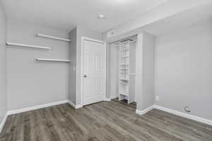 Unfurnished bedroom with a closet, wood finished floors, visible vents, and baseboards