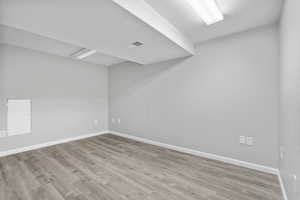 Empty room with baseboards, visible vents, and wood finished floors