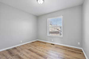 Empty room with baseboards, visible vents, and wood finished floors