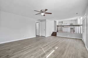 Unfurnished living room with baseboards, visible vents, ceiling fan, stairs, and light wood-style floors