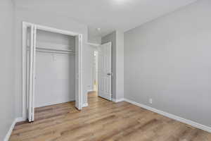 Unfurnished bedroom with light wood-type flooring, baseboards, and a closet