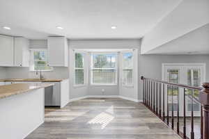 Kitchen featuring a sink, light wood-style floors, white cabinets, stainless steel dishwasher, and tasteful backsplash