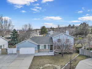 Split level home with a garage, concrete driveway, a shingled roof, and fence