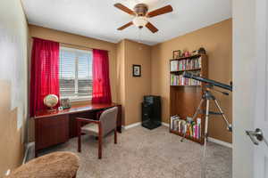 Carpeted home office with a ceiling fan, baseboards, and a textured ceiling