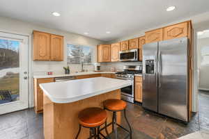 Kitchen featuring stone tile flooring, a healthy amount of sunlight, stainless steel appliances, and a sink