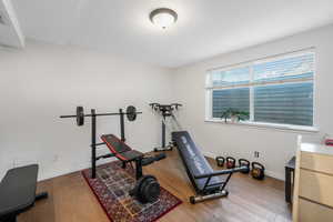 Workout area with hardwood / wood-style floors and baseboards