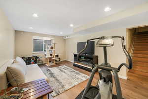 Workout room with a glass covered fireplace, recessed lighting, baseboards, and wood finished floors