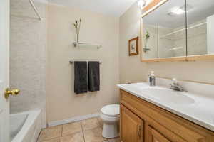 Bathroom with toilet, a textured ceiling, tile patterned flooring, baseboards, and vanity