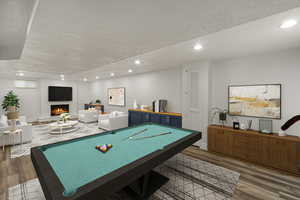 Game room with a large fireplace, wood finished floors, pool table, a textured ceiling, and recessed lighting