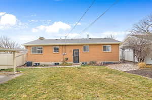 Back of house featuring fence, a lawn, and brick siding