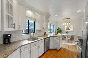 Kitchen featuring a wainscoted wall, a sink, white cabinetry, appliances with stainless steel finishes, and light wood finished floors