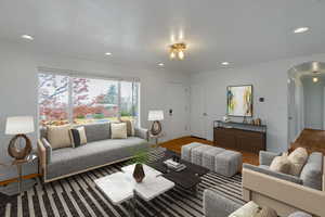 Living area featuring arched walkways, ornamental molding, wood finished floors, and recessed lighting