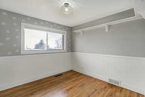 Spare room featuring visible vents, wood finished floors, and wainscoting