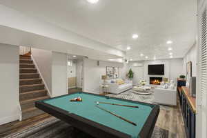 Playroom with recessed lighting, a large fireplace, a textured ceiling, wood finished floors, and baseboards