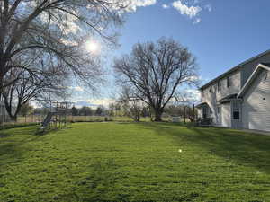 View of yard with a playground and fence
