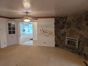 Unfurnished living room with heating unit, carpet floors, baseboards, a fireplace, and a textured ceiling