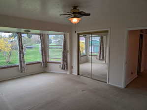 Unfurnished bedroom featuring light colored carpet, ceiling fan, baseboards, and visible vents