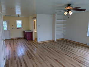 Interior space with baseboards, a ceiling fan, a sink, and light wood finished floors
