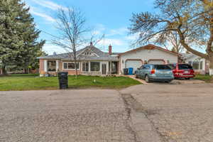 View of front facade with brick siding, a garage, driveway, and a front lawn