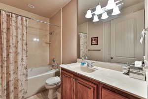 Full bathroom featuring toilet, tile patterned flooring, shower / bath combo with shower curtain, and vanity