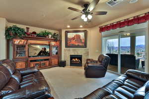 Living area featuring visible vents, ceiling fan, a textured ceiling, carpet floors, and a fireplace
