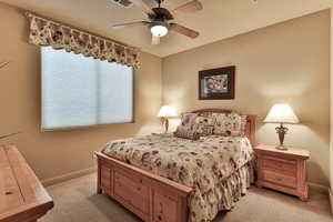 Bedroom featuring a ceiling fan, light colored carpet, visible vents, and baseboards