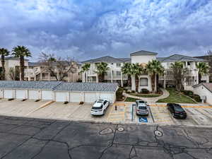 View of front of house with uncovered parking, a residential view, community garages, and stucco siding
