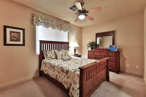 Bedroom with light carpet, ceiling fan, and baseboards