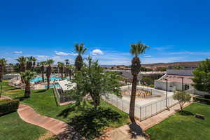 View of community featuring a lawn, a swimming pool, and fence