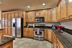 Kitchen featuring brown cabinets, light tile patterned floors, and stainless steel appliances