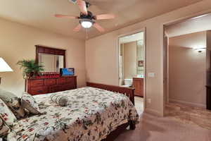 Bedroom featuring light colored carpet, connected bathroom, baseboards, and ceiling fan