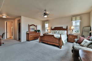 Bedroom with a textured ceiling, ceiling fan, multiple windows, and light colored carpet