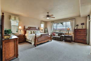 Carpeted bedroom featuring a ceiling fan and a textured ceiling