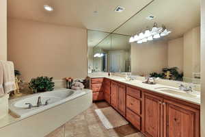 Full bath featuring a garden tub, double vanity, a sink, and visible vents