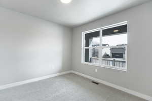 Carpeted empty room with visible vents and baseboards