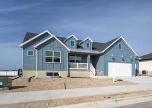 View of front of house with metal roof, a porch, a garage, concrete driveway, and board and batten siding