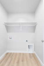 Washroom with hookup for a washing machine, electric dryer hookup, wood finished floors, laundry area, and baseboards