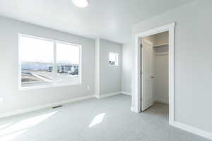 Unfurnished bedroom with baseboards, visible vents, a walk in closet, and light colored carpet