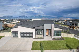 Contemporary home featuring a mountain view, driveway, and fence