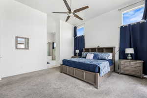 Carpeted bedroom with baseboards, ceiling fan, and ensuite bath