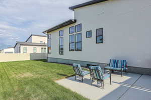 Rear view of property featuring a patio, a yard, and fence