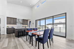Dining area featuring a towering ceiling, light wood-style flooring, and baseboards
