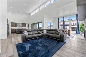 Living room featuring a towering ceiling, light wood-style flooring, and recessed lighting