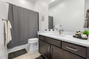 Bathroom featuring toilet, tile patterned flooring, shower / bathtub combination with curtain, and vanity