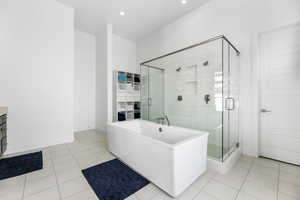 Bathroom featuring a freestanding bath, a stall shower, baseboards, and tile patterned floors