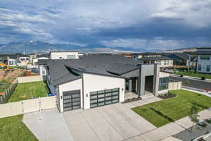 Contemporary home featuring a mountain view, a garage, fence, roof with shingles, and a gate