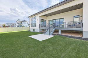Back of house with stucco siding, fence, and a yard