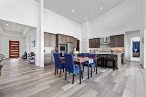 Dining space with a high ceiling, light wood-style flooring, and recessed lighting
