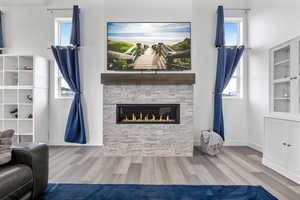 Living room featuring a stone fireplace, baseboards, and wood finished floors