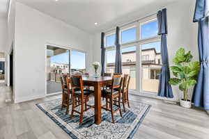 Dining room with light wood-type flooring, baseboards, a high ceiling, and recessed lighting